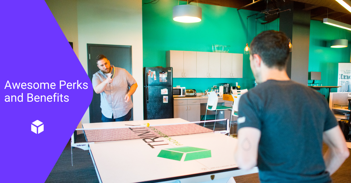 Two men playing ping pong in an office