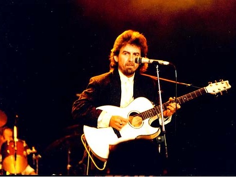 George Harrison plays guitar onstage